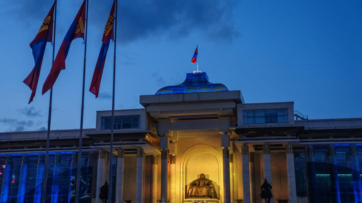 Mongolian flags around the State Great Khural, or parliament building, in central Ulaanbaatar at dusk.
