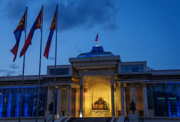 Mongolian flags around the State Great Khural, or parliament building, in central Ulaanbaatar at dusk.